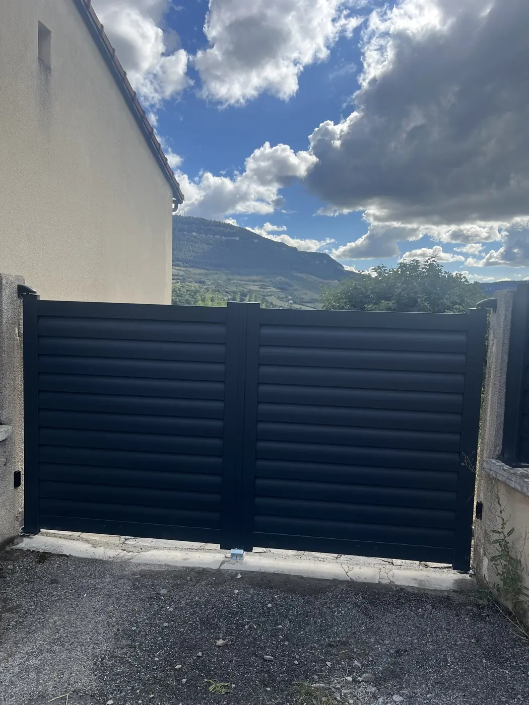 Portail aluminium anthracite devant un paysage des causses